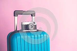 Luggage with vintage old fashioned camera on rose background minimalistic vacation concept