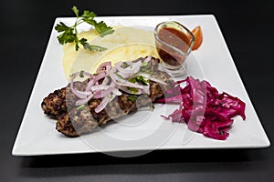 Lula kebab.Kebab.Traditional Oriental dish, barbecue shish kebab. Lamb, onions, cabbage, mashed potatoes spicy tomato sauce on pla