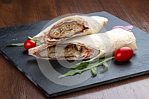 Lula kebab in lavash with salads and vegetables on a stone board