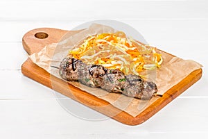 Lula kebab with vegetables on a wooden board and white background