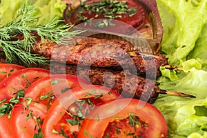 Lulia kebab on a salad with tomatoes and dill