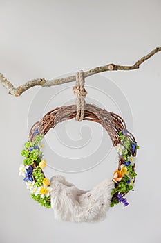 Lullaby of grapevine ring with spring flowers for newborn children hanging on a branch on a white background