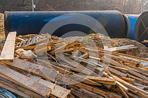 Lumber scattered in front of industrial pipes