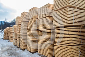 Lumber warehouse in the open air. Wooden beam, planks of wood, stacked in stacks. Construction material