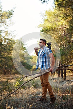 Lumberjack with an ax and firewood in forest.