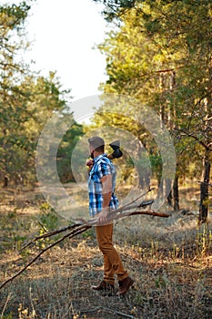 Lumberjack with ax and firewood goes through forest.