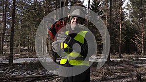 Lumberjack with chainsaw on shoulder in forest with camera shaking
