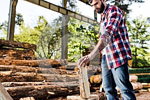 lumberjack in checkered shirt preparing to chop half of log photo