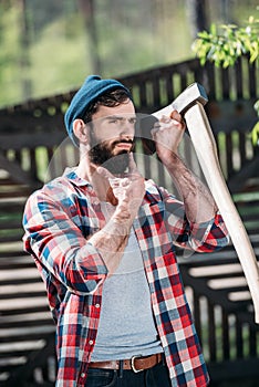lumberjack in checkered shirt shaving beard by axe photo