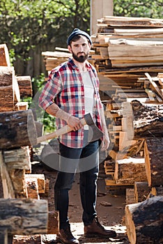 lumberjack in checkered shirt standing with axe between logs photo