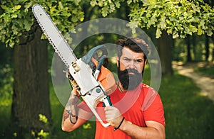 Lumberjack on serious face carries chainsaw. Deforestation is a major cause of land degradation and destabilization of