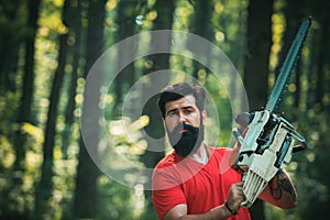 Lumberjack in the woods with chainsaw axe. Professional lumberjack holding chainsaw in the forest. Woodworkers