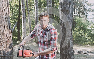 Lumberjack worker with chainsaw in the forest. Professional lumberjack holding chainsaw in the forest. Lumberjack