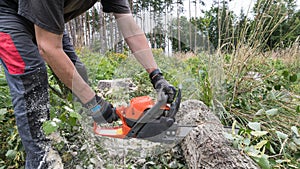 Lumberjack working with power chain saw at cutting wooden log