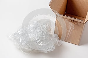 A lump of crumpled cellophane packing filler next to a cardboard box