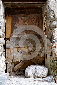 Lump of rock in front of an old morbid door