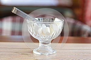 Lump sugar in crystall vase with sugar tongs closeup photo on cafe interior background