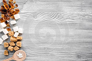 Lumps of sugar in spoons on gray table background top view space for text