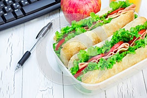 Lunch box with ciabatta bread sandwiches on workplace