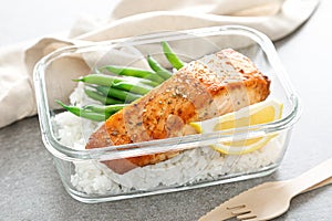 Lunch box containers with grilled salmon fish fillet, rice and green beans