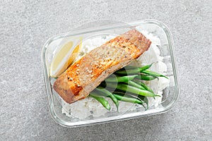 Lunch box containers with grilled salmon fish fillet, rice and green beans