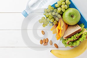 Lunch box with healthy food for school children with bottle of water on white wooden background.