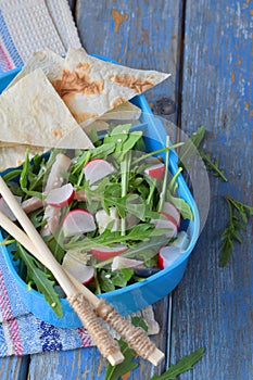 Lunch Box with salad of fresh vegetables - arugula, radish, feta cheese, ham and sesame with flat bread tortilla. Healthy food. Lu