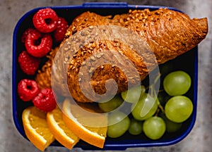 Lunch box with a sandwich croissant and fruit healthy snacks for school