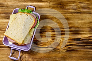 Lunch box with sandwiches on wooden table. Top view, copy space