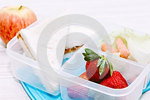 Lunch box with vegetables and slice of bread for a healthy school lunch on wooden table