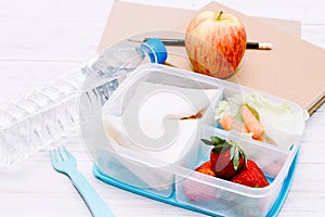 Lunch box with vegetables and slice of bread for a healthy school lunch on wooden table