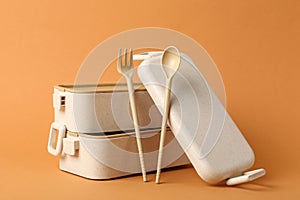 Lunch boxes and cutlery on orange background. Conscious consumption