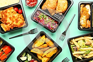 Lunch boxes with delicious meals and forks on color background, closeup