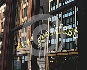 Lunch breakfast gold letters in restaurant window with city reflection