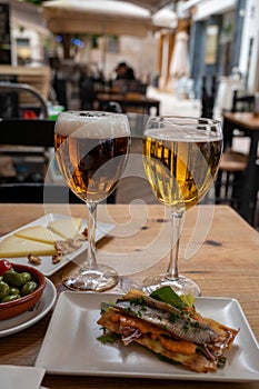 Lunch with cold beer in Spanish outdoor cafe, different tapas, fish, green olives and Spanish cheese manchego with nuts, Malaga,