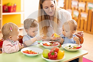 Lunch in nursery. Educator feeding babies