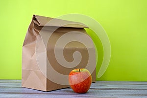 Lunch packed in a brown paper bag with red apple