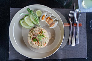 Lunch rice mixed with traditional chilli paste, shrimp, eat with salted eggs, cucumber, lime, etc. on white plate on granite table