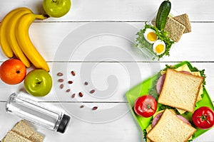 Lunch. Sandwich and fresh vegetables, bottle of water, nuts and fruits on white wooden background. Healthy eating