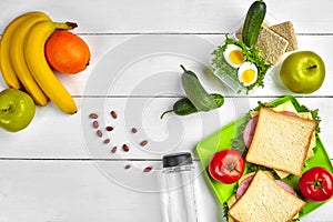 Lunch. Sandwich and fresh vegetables, bottle of water, nuts and fruits on white wooden background. Healthy eating