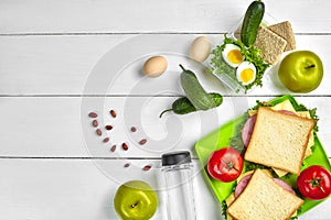 Lunch. Sandwich and fresh vegetables, bottle of water, nuts and fruits on white wooden background. Healthy eating