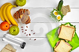 Lunch. Sandwich and fresh vegetables, bottle of water, nuts and fruits on white wooden background. Healthy eating