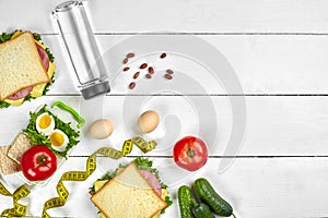 Lunch. Sandwich and fresh vegetables, bottle of water, nuts and fruits on white wooden background. Healthy eating