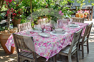 Lunch table with empty dish set on colorful tablecloth and bouquet of freshly picked garden flowers