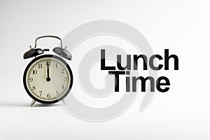 LUNCH TIME inscription written and alarm clock on white background