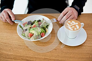 Lunch time Male worker eating his delicious and healthy meal. Man enjoying salad and flat white. Take care of yourself and don't