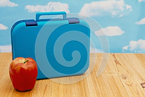 Lunchbox with apple on wood desk with the sky photo