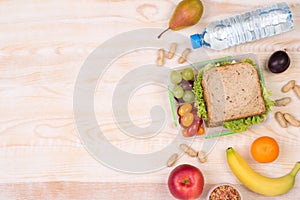 Lunchbox with sandwich, fruits, vegetables, and water with copy space