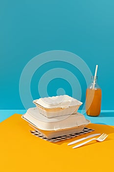 Lunchboxes, cutlery and drinks on orange table. Food delivery concept