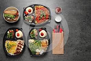 Lunchboxes with different meals on grey table, flat lay